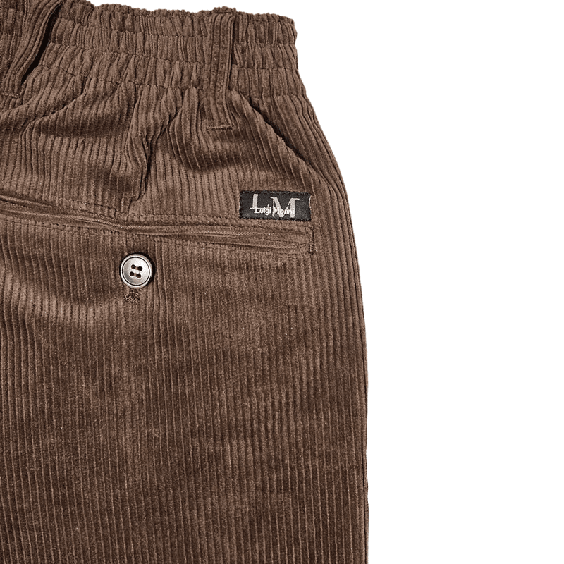 Close-up detail van bruin corduroy, elastische tailleband, riemlus, achterzak met knoop en merklabel